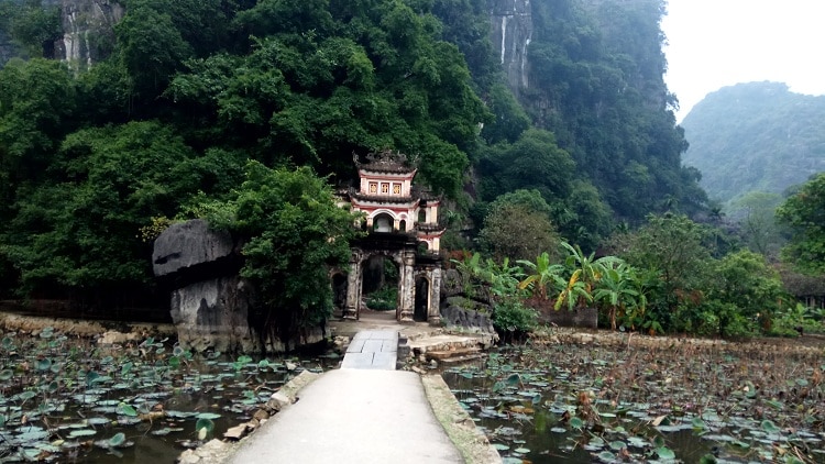 Premium Photo  Lone tourist with traditional vietnamese hat at bich dong  pagoda entrance gate, ninh binh vietnam, buddhist temple set amid jungle  and karst mountain range. traveling alone, keep social distancing.