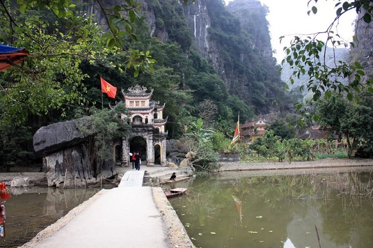 Premium Photo  Lone tourist with traditional vietnamese hat at bich dong  pagoda entrance gate, ninh binh vietnam, buddhist temple set amid jungle  and karst mountain range. traveling alone, keep social distancing.